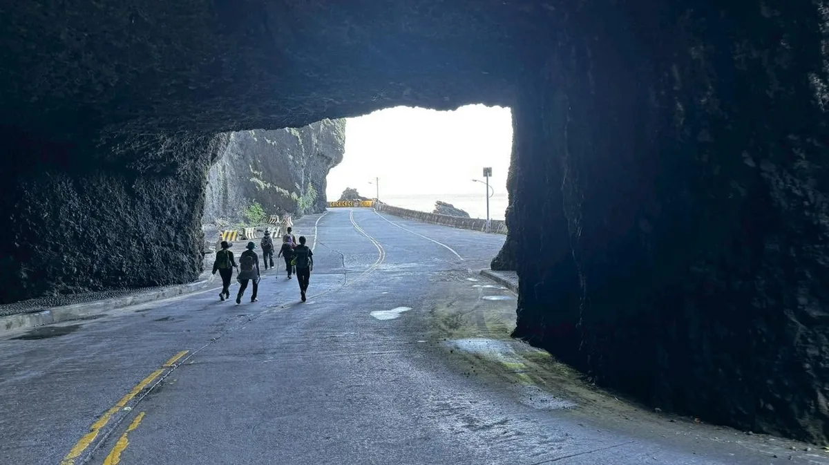 夥伴步行穿過海蝕洞形成的公路隧道,洞口外是海