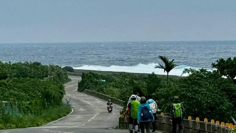 從高處俯瞰海岸公路與海灣,路旁有夥伴正在行走