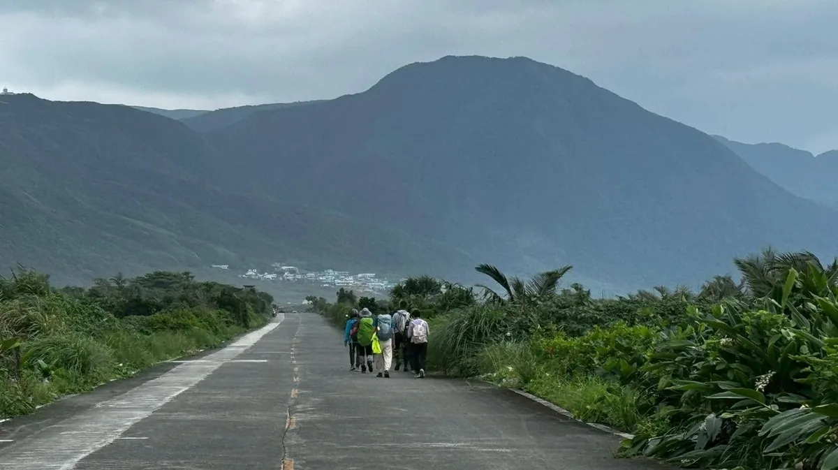 夥伴走在通往村落的公路上,遠方是連綿的山