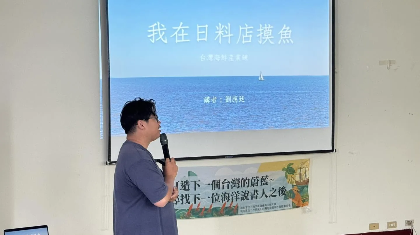 劉應廷在投影幕前講課,投影片標題是「我在日料店摸魚——台灣海鮮產業鍊」