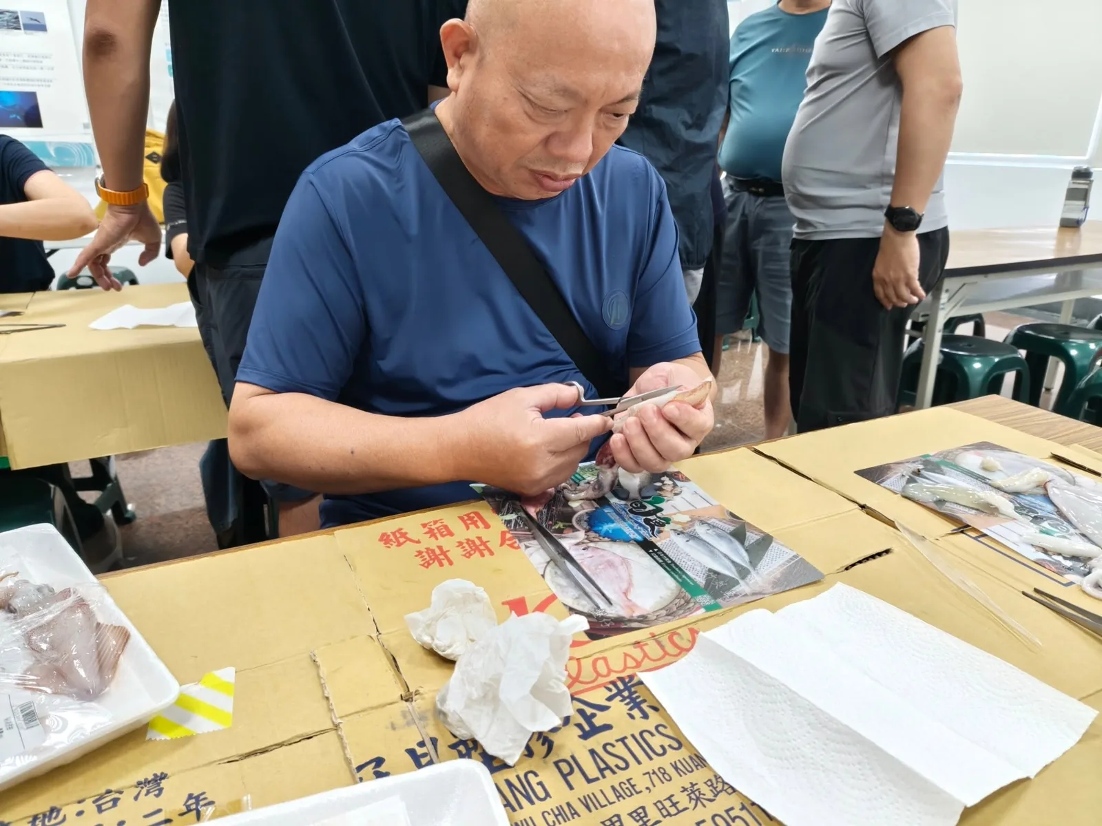 年長男性學員用鑷子夾起手中的小卷仔細端詳