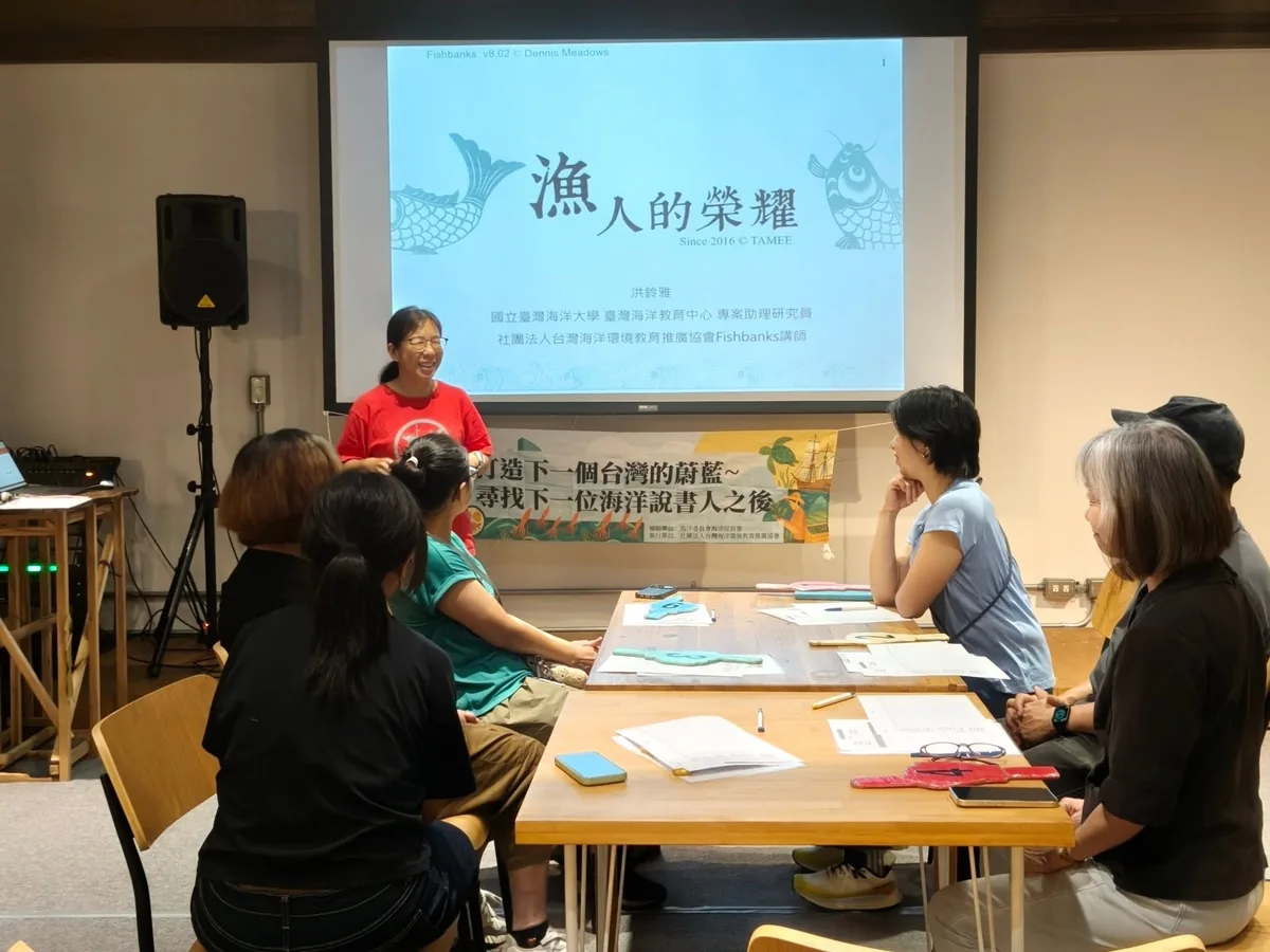 講師站在「漁人的榮耀」投影幕前,學員圍著長桌討論