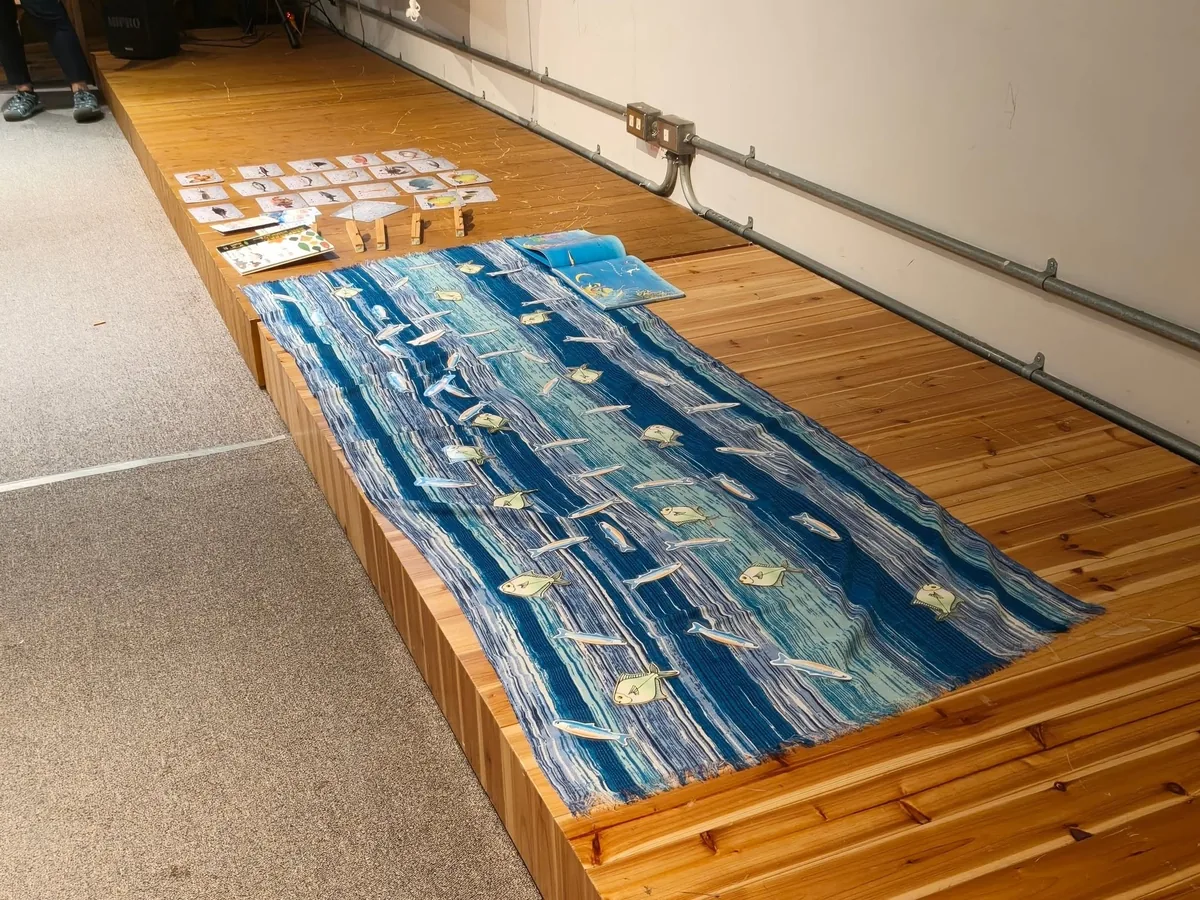 木地板上鋪開的藍色海洋圖布教具,周圍擺著魚類卡牌