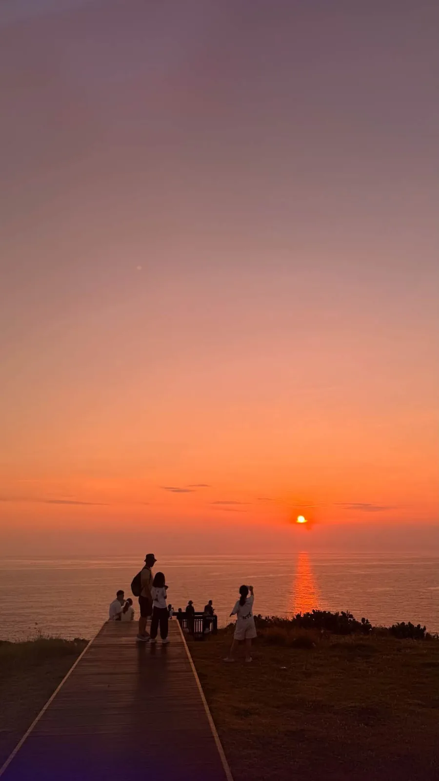 夕陽沉入海面,望安海邊棧道上的人影成為剪影