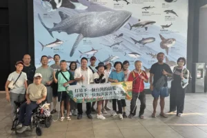 說書人台東場學員在水族生態研究館的巨幅海洋生物壁畫前，拉著「打造下一個台灣的蔚藍」布條合影