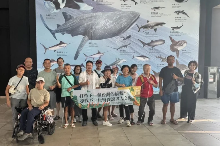 說書人台東場學員在水族生態研究館的巨幅海洋生物壁畫前，拉著「打造下一個台灣的蔚藍」布條合影
